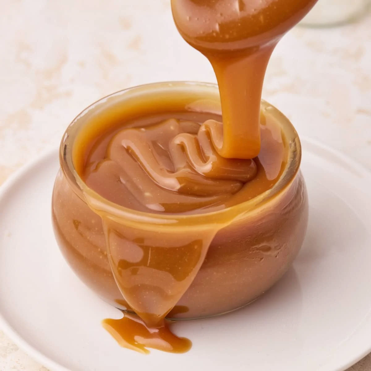 Saus karamel kental dituangkan ke dalam mangkuk kaca